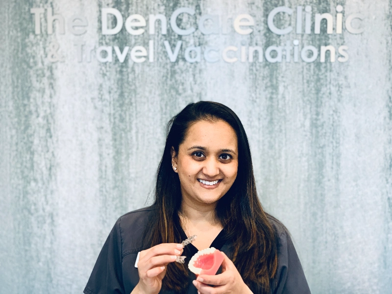 Smiling dentist holding dental model and aligner